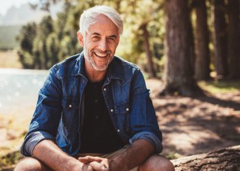 Happy mature man sitting near a lake