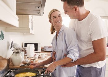 Affectionate Mature Couple Prepare Breakfast In Kitchen Together